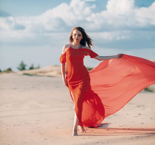 elegante vrouw die zich voordeed op het strand met rode jurk