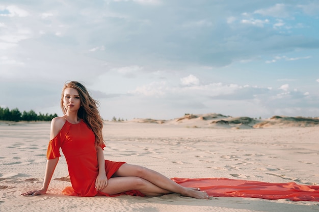 elegante vrouw die zich voordeed op het strand met rode jurk