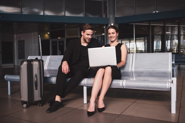 Elegante vrouw en man aan het werk op een laptop op de luchthaven