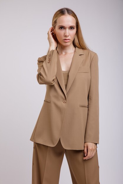 Elegante vrouw in beige bruin pak buttondown broek jasje op witte achtergrond Slank figuur