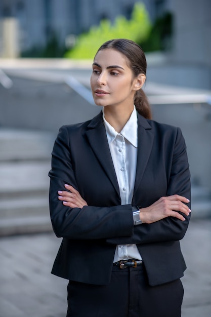 Elegante vrouw in een zwart pak met gevouwen armen