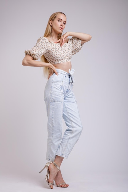 elegante vrouw in mooie blauwe denim jeans, beige met bloemmotief op een witte achtergrond