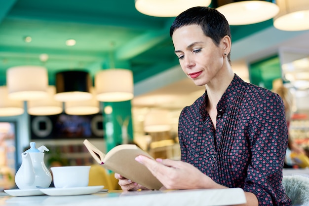 Elegante vrouw leesboek in Cafe