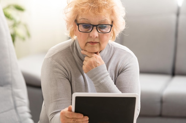 elegante vrouw van middelbare leeftijd die tablet-pc thuis gebruikt.