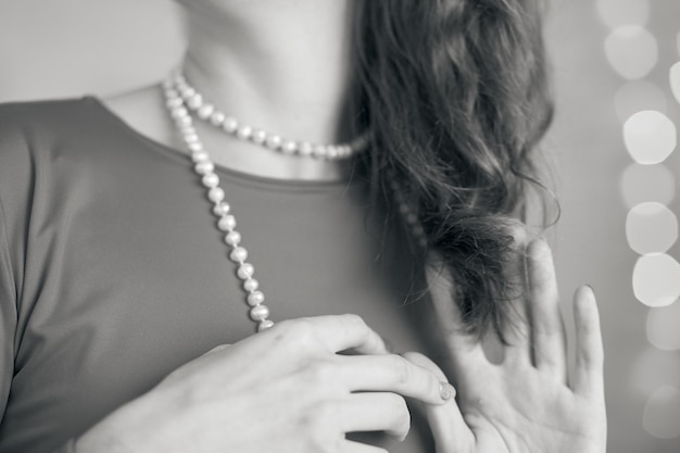 Elegante vrouwelijke sieraden witte kralen op vrouw op bokeh achtergrond close-up Kerstmis en Nieuwjaar cadeau concept Zwart-wit fotografie