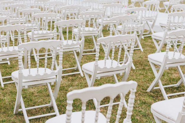 Elegante witte stoelen op een gazonopstelling voor huwelijksceremonie