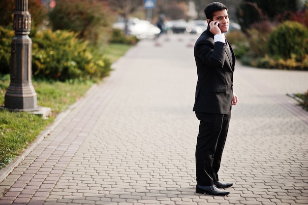 Elegante Zuid-Aziatische zakenman in pak spreken op mobiele telefoon.