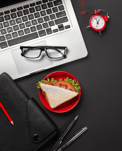 Elegante zwarte office desktop met laptop kopje koffie en een broodje voor de lunch Bovenaanzicht