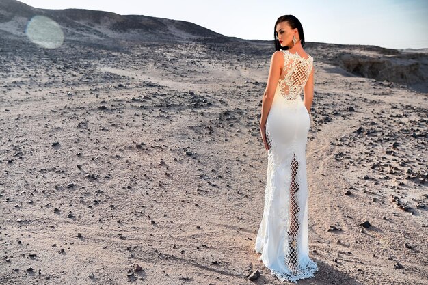 Elegantie en fashion model Bruiloft mode en schoonheidssalon Vrouw in witte jurk in zandduinen Meisje in jurk in zonnige woestijn Bruid en huwelijksceremonie