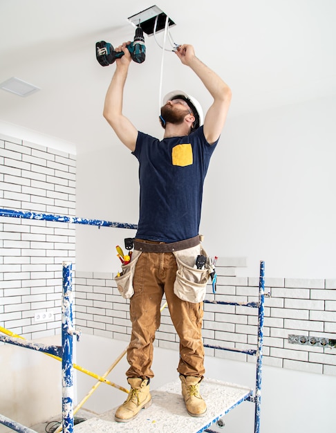 Elektricien bouwer aan het werk, installatie van lampen op hoogte.