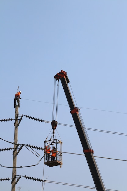 Elektricien die op hoogte werken door een hoogspanningsdraad aan te sluiten