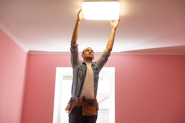 Elektricien die verlichting controleert aan het plafond in huis, technicusconcept