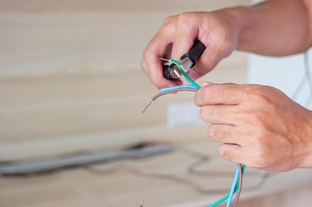 Elektricien knipt elektrische draden door met een tang bedradingskabels installatie voor wandcontactdoos bevestiging renovatie reparatieservice en ontwikkeling van woning- en appartementconcepten