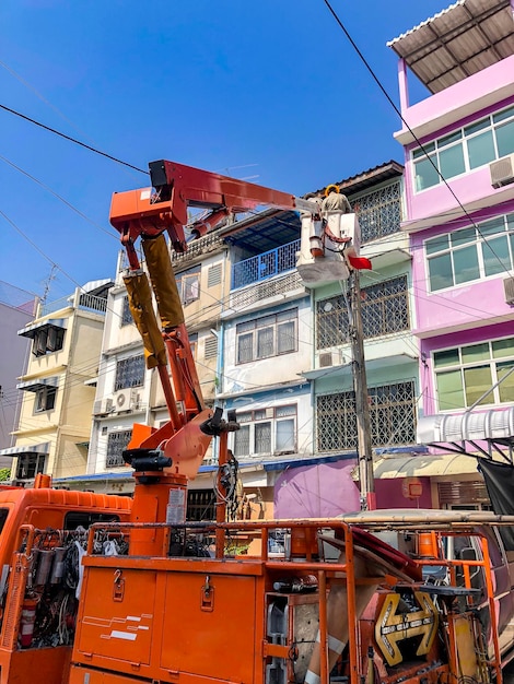 Elektricien op de vrachtwagenkraan ging omhoog om de hoofdstroomleiding in het Soi ManSri-gebied PomPrab Bangkok Thailand te controleren en te repareren