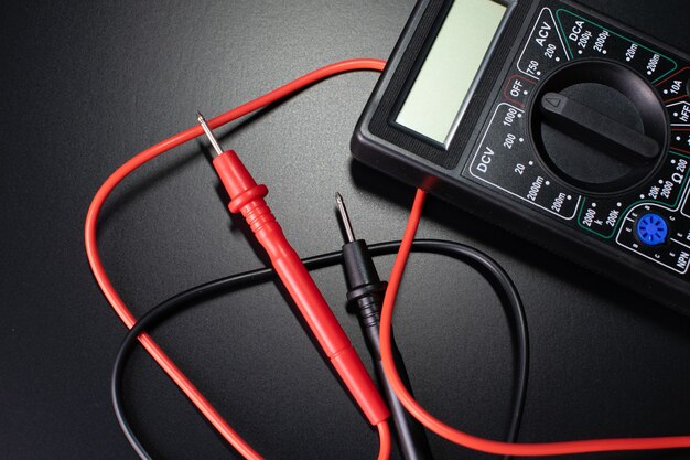 elektricien tools op zwarte tafel, digitale multimeter op zwarte tafel