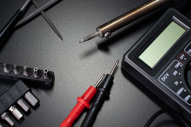 elektricien tools op zwarte tafel, digitale multimeter op zwarte tafel