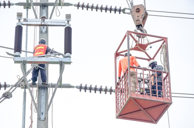 Elektriciens klimmen op elektrische palen om hoogspanningsleidingen te installeren en te repareren.