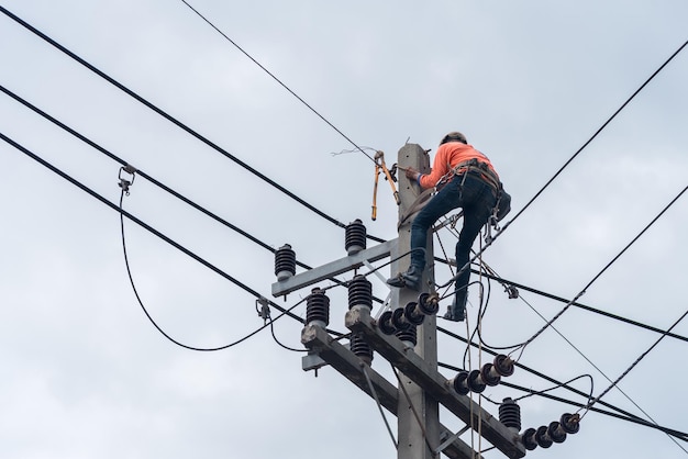 Elektriciens klimmen op elektrische palen om hoogspanningsleidingen te installeren en te repareren.