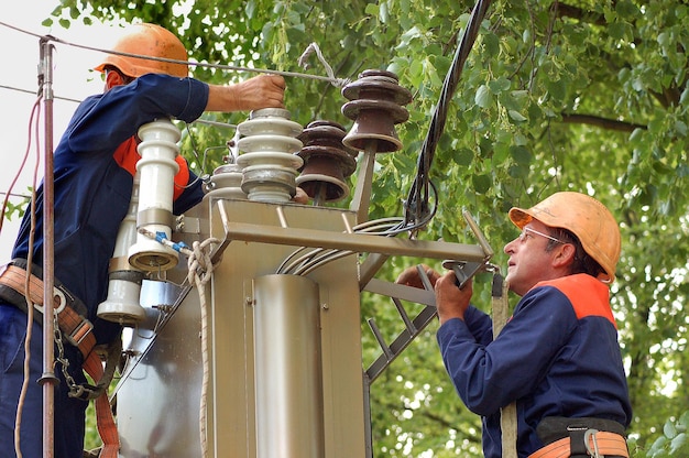 Elektriciens repareren en vervangen de beschadigde isolator in de elektrische schakelkast.