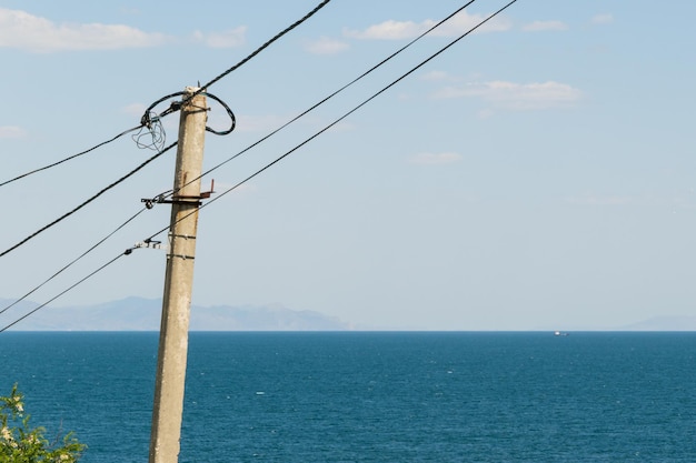 Elektriciteit en de Krim Elektrische paal met draden op de achtergrond van de Krimzee