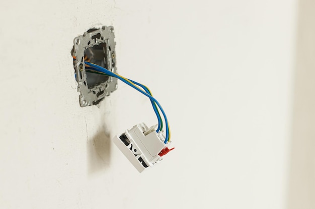 Elektriciteitskast met stopcontact en schakelaar Elektriciteitsconnector installeren in gepleisterde muur Bouw van huis en huisrenovatieconcept Bekabeling