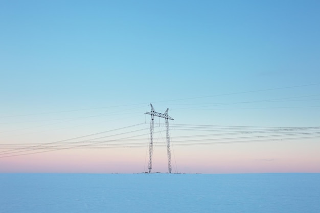 Elektriciteitslijn in leeg winterveld bij pastelzonsondergang