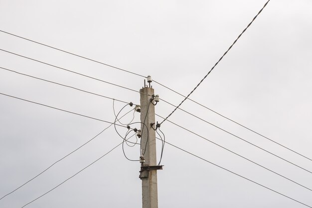 Elektriciteitspaal met stroomdraden lijn in een bewolkte dag