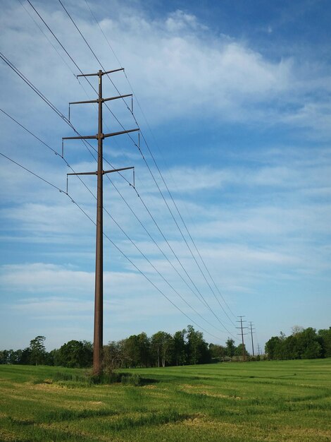 Foto elektriciteitspalen op een grasveld tegen een bewolkte lucht