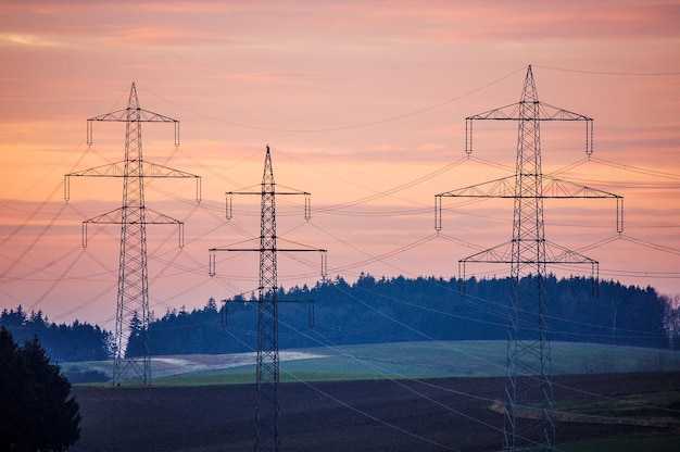Elektriciteitspylon op het landschap tegen de hemel bij zonsondergang