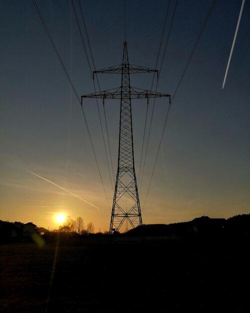 Elektriciteitspylon op het veld tegen de hemel tijdens zonsondergang