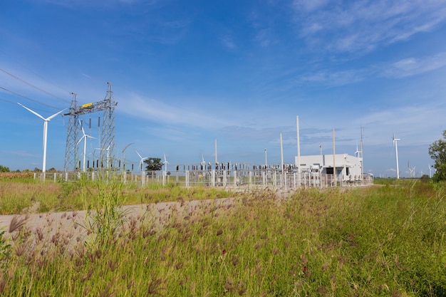 Elektriciteitspylonen en elektrische centrale of station met windturbine in aard openlucht