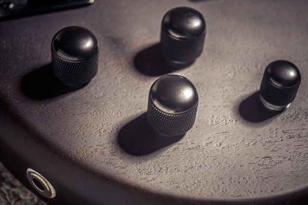 Elektrische basgitaar met vier snaren close-up Detail van populaire rockmuziekinstrument Macro vintage foto van bedieningsknoppen van bruine gitaar