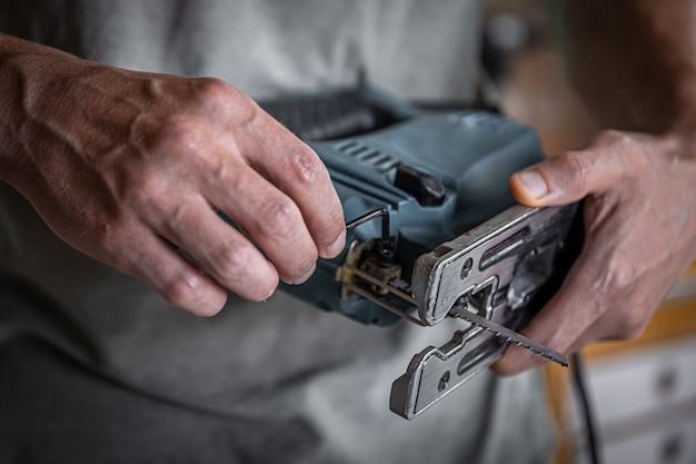 Foto elektrische decoupeerzaag met een zaag voor hout in handen van timmerman.