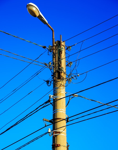 Elektrische draad en lamp op elektropool met blauwe hemel