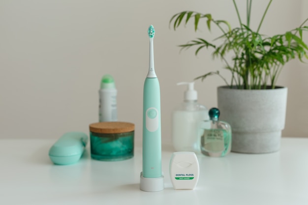Elektrische draadloze ultrasone tandenborstel met tandzijde die zich in lichte badkamers bevinden