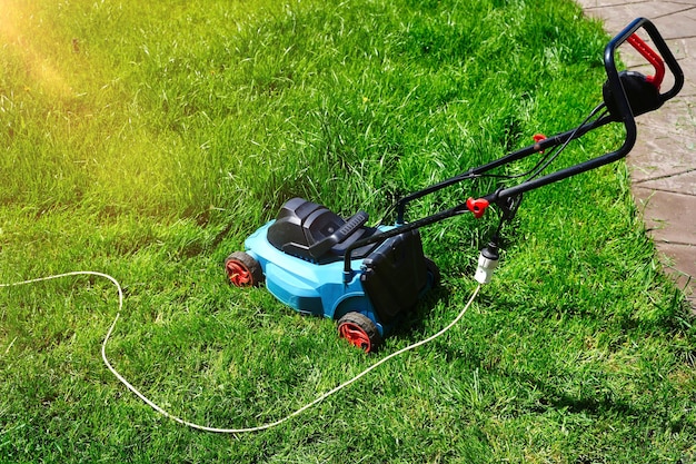 Elektrische grasmaaier die groen gras trimt Gazon maaien zomertijd