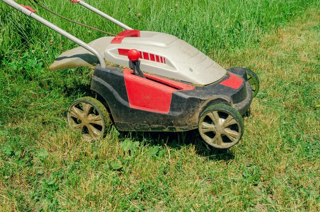 Elektrische hand grasmaaier maait het gras close-up zijaanzicht