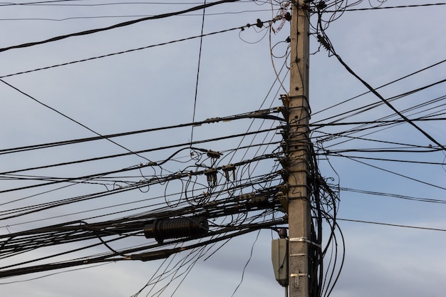 Elektrische paal met rommelige draden en kabels op blauwe hemelachtergrond