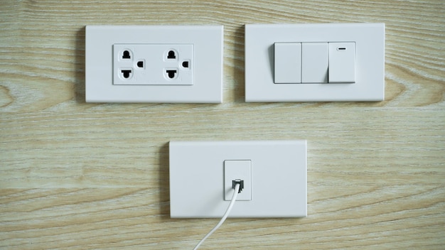 Elektrische schakelaar en stekker op houten muur Stekkers en stopcontacten Witte stekkers en stopcontact voor kabel-tv aan de muur