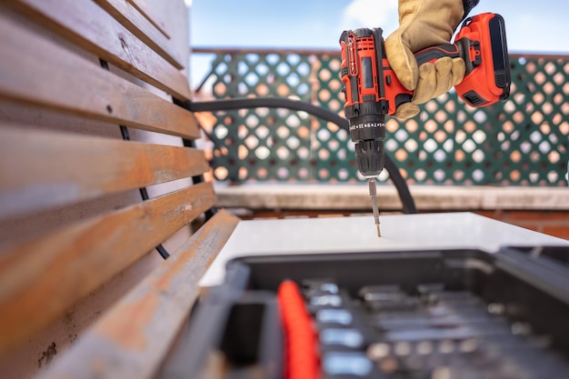 Elektrische schroevendraaier op batterijen door een schroef in een hout naast de gereedschapskist te steken