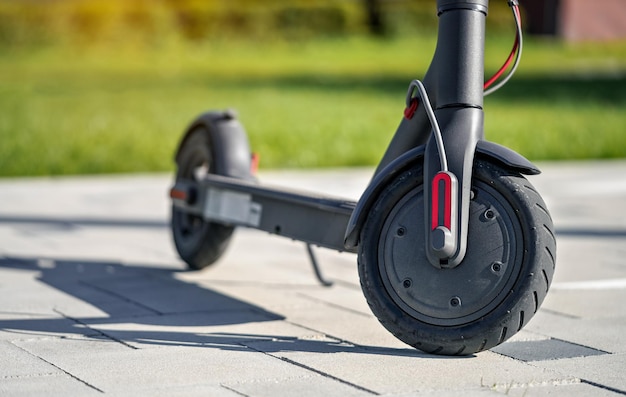 Elektrische scooter geparkeerd op betegelde stenen bestrating - close-up detail op voorwiel.