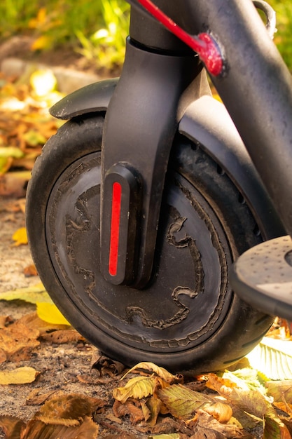 Elektrische scooter in gele herfstbladeren close-up