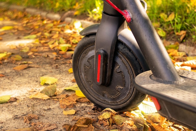 Elektrische scooter in gele herfstbladeren close-up