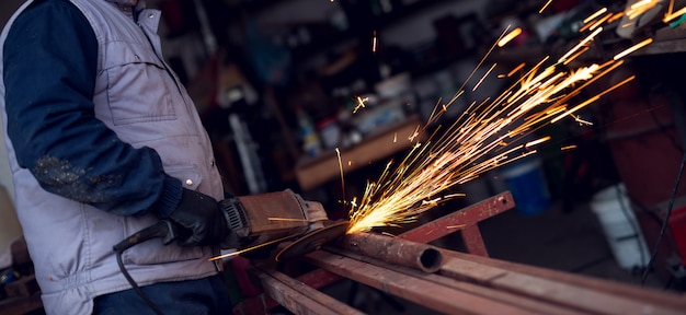 Elektrische wiel slijpen op een stalen structuur in de fabriek.