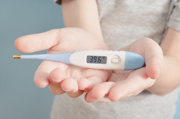 Elektronische thermometer in handen van kinderen. Verhoogde lichaamstemperatuur. Detailopname