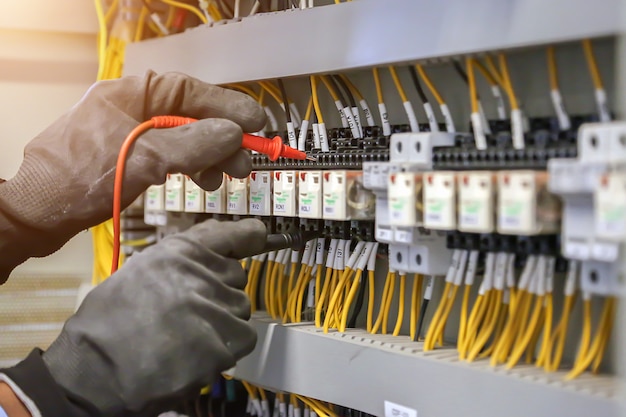 Elektrotechnicus die digitale multimeter gebruikt om de stroomspanning bij de stroomonderbreker in het hoofdverdeelbord te controleren.