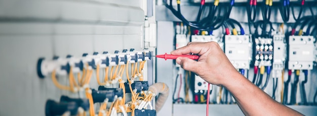 Elektrotechnisch ingenieur die de werking van de elektrische schakelkast controleert, onderhoudsconcept.