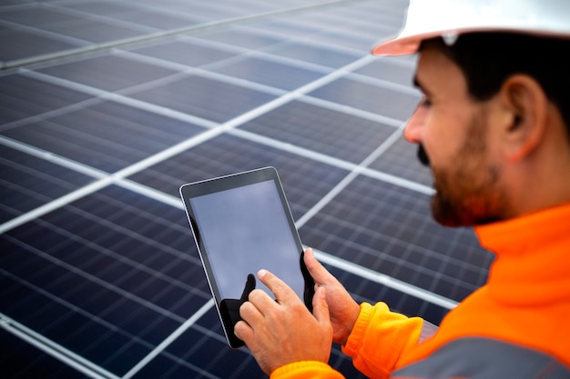 Elektrotechnisch ingenieur die digitale tablet met zonnepanelenschema vasthoudt en productiviteit controleert