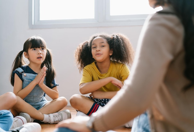 Elementaire internationale studenten zitten op de vloer in een cirkel rond de leraar en luisteren naar een verhaal in hun klas. De leraar leest een verhaal uit een boek. Onderwijs, school, leren, concept