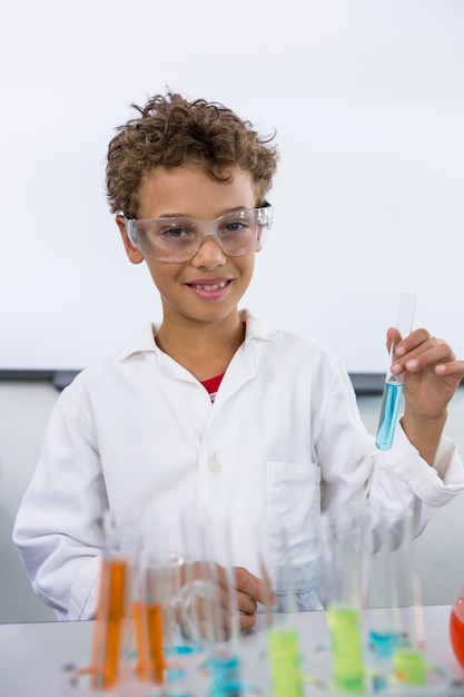 Elementary of boy holding test tube with liquid at laboratory